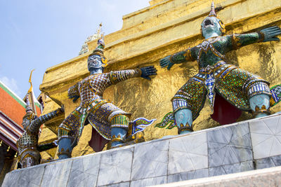 Low angle view of statues on building against sky