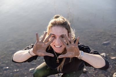 Woman with muddy hands smiling while having fun outdoors in nature.