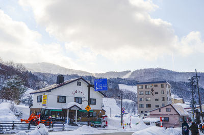 Road by buildings against sky during winter