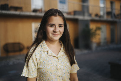 Portrait of smiling girl standing in front of residential building