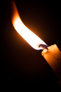 Close-up of lit candle against black background