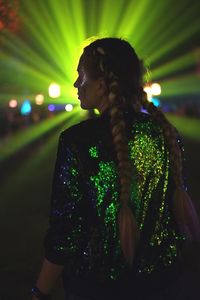 Woman looking at illuminated camera at night