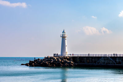 Lighthouse by sea against sky