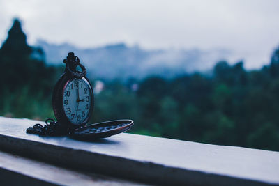 Close-up of clock on table against sky