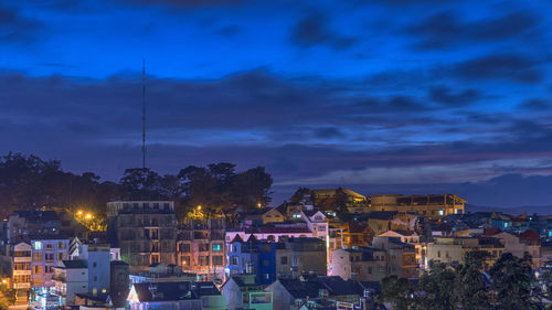 Illuminated buildings against blue sky in city at night