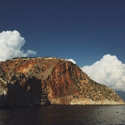 Scenic view of sea by mountain against sky