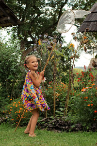 Happy 5-6 years old girl catching a butterfly in the village garden at summer