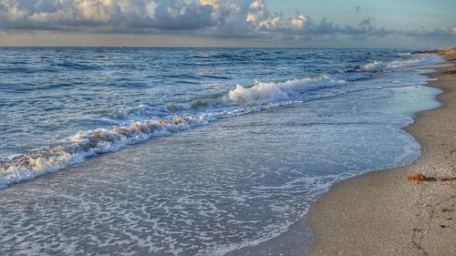 Scenic view of waves rushing towards shore against sky