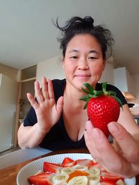 Portrait of woman holding strawberry at home