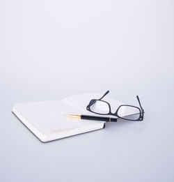 Close-up of eyeglasses on book against white background