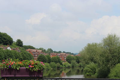 Scenic view of lake by trees and buildings against sky