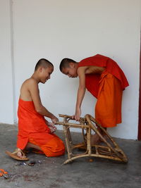 Side view of two men standing against wall