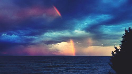 Scenic view of rainbow over sea against sky