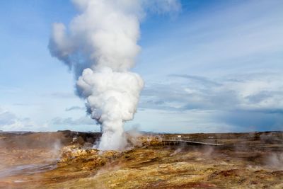 Smoke emitting from volcanic landscape against sky