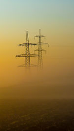 Silhouette electricity pylon against sky during sunset