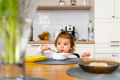 Cute girl eating food at table