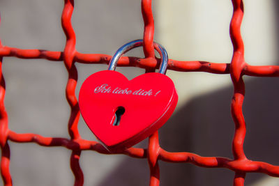 Close-up of red heart shape padlock on metallic fence