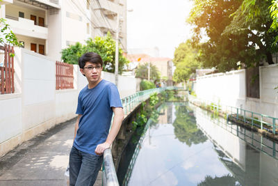 Portrait of young man standing against buildings