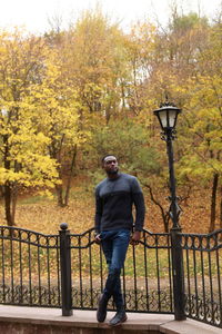 Rear view of man standing by railing during autumn