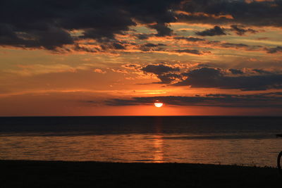 Scenic view of sea against dramatic sky during sunset