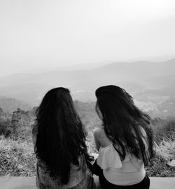 Rear view of women looking at mountains against sky