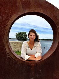 Portrait of woman looking through hole at beach