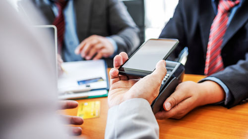 Midsection of man using smart phone on table