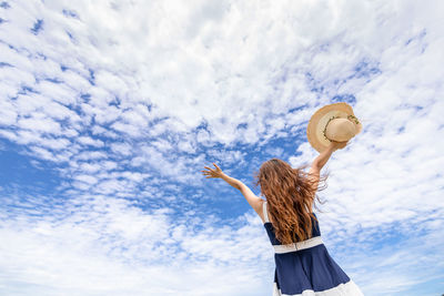 Low angle view of woman standing against sky