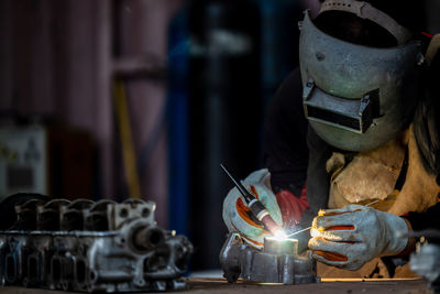 Welder in face mask welds with argon arc stainless steel welding, industrial worker at the factory.