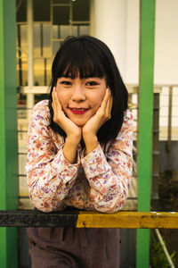 Portrait of woman standing against railing