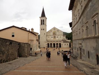 People walking in historic building against sky in city