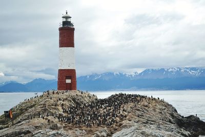 Lighthouse by sea against sky