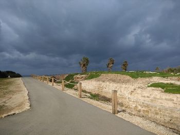 Road leading towards land against sky