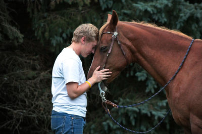 Young man leaning on horse