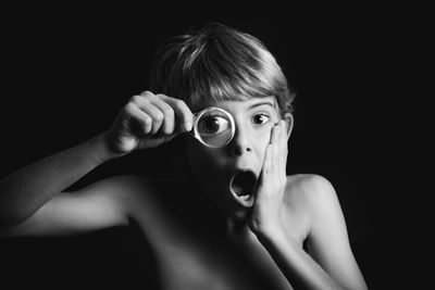 Close-up portrait of shirtless boy against black background