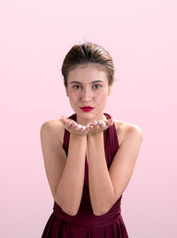 Portrait of young woman against pink background