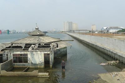 Rear view of man on sea against buildings