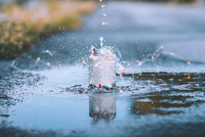 Close-up of water splashing in container on wet street 
