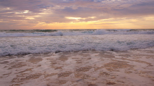 Waves rushing towards shore during sunset