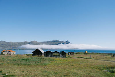 Huts on riverbank against clear blue sky