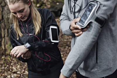 Male and female athletes wearing smart watch and arm band in forest