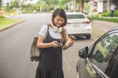 Full length of woman using phone while standing on road