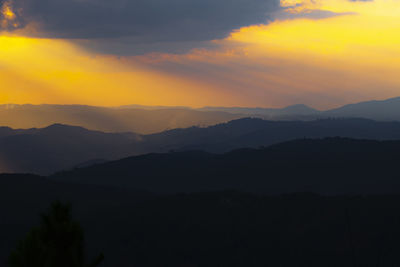 Scenic view of silhouette mountains against orange sky