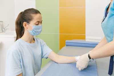 Nurse bandaging patient in clinic