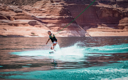 Man kiteboarding in sea against rock formations