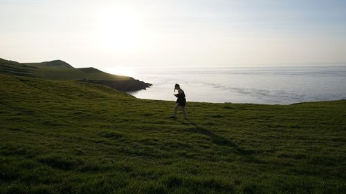 Man standing on shore by sea against sky