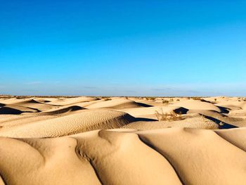 Sand dunes in desert against clear blue sky