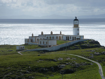 Lighthouse by sea against sky