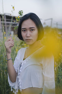 Portrait of beautiful woman standing against yellow plants