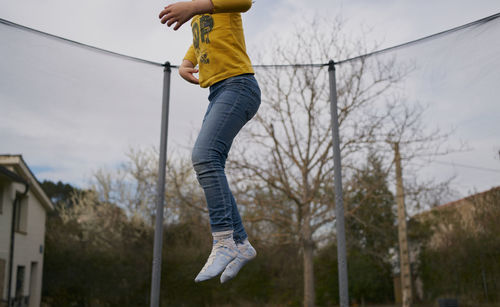A girl in casual clothes jumping on a trampoline